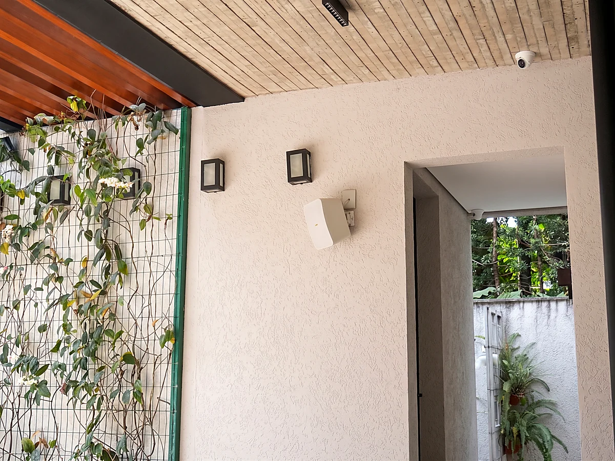 Muro verde com arandelas externas e acesso coberto em casa residencial entregue pela HC Engenharia