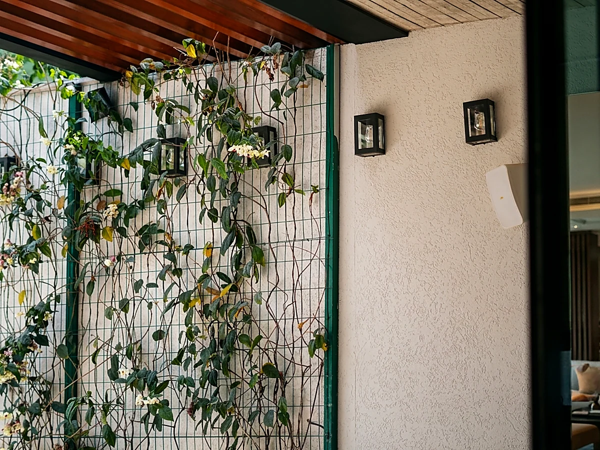 Muro verde com treliça e arandelas externas em casa residencial entregue pela HC Engenharia