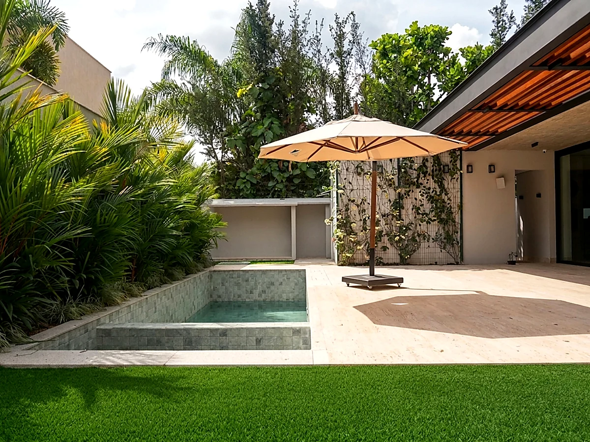 Piscina com deck em travertino e ombrelone, vista da varanda de casa residencial entregue pela HC Engenharia